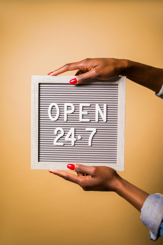 Services Close-up of hands holding a letter board with Open 24-7 message on a warm background.